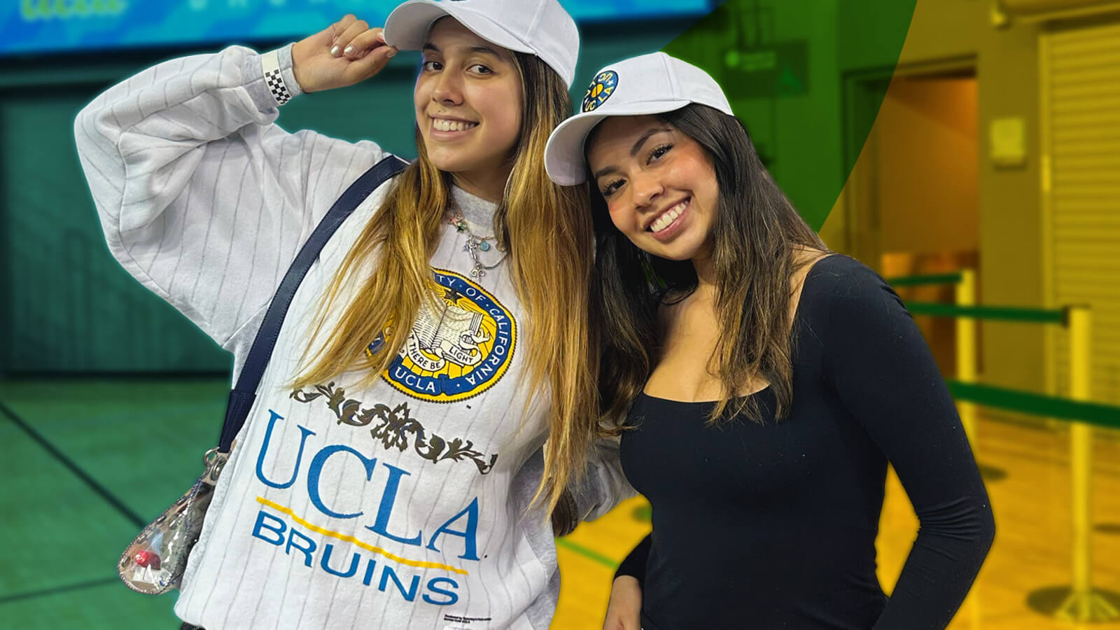 two women smiling wearing college hats and a sweatshirt