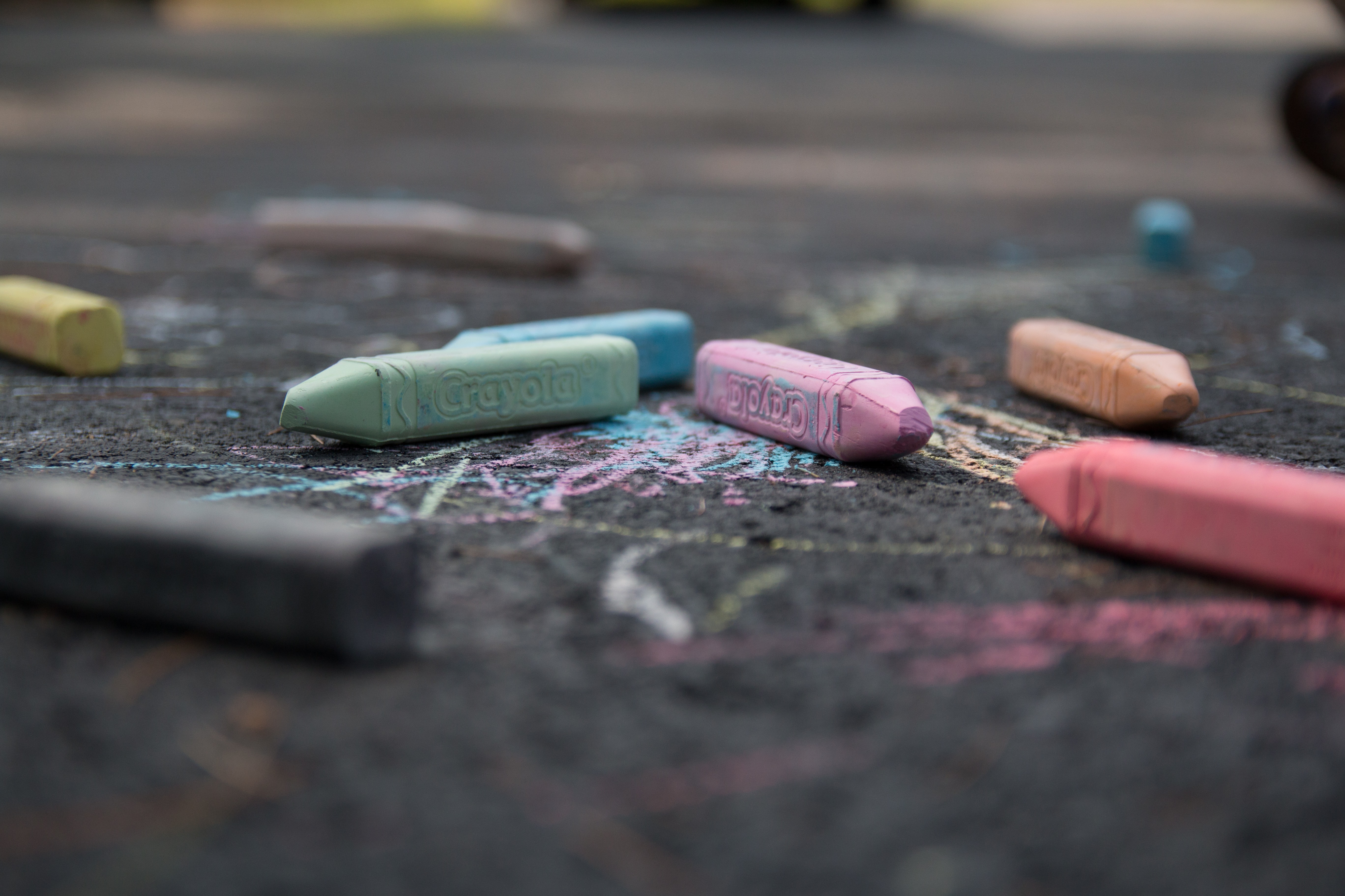 Crayola chalk laying on cement amid a bunch of scribbles.