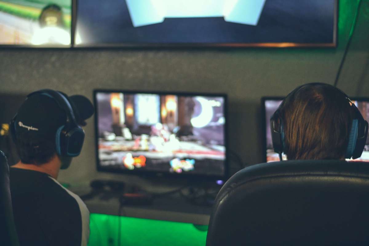 two guys seen from the back playing video games