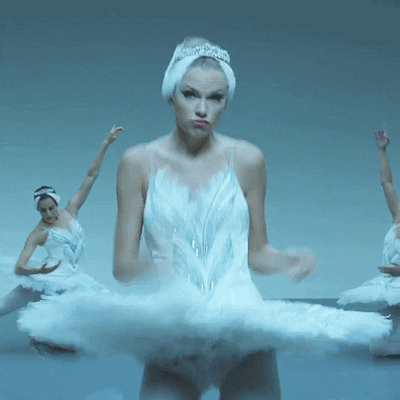 Singer Taylor Swift dancing in her music video for the song "Shake It Off" wearing a white ballerina costume and tutu. 
