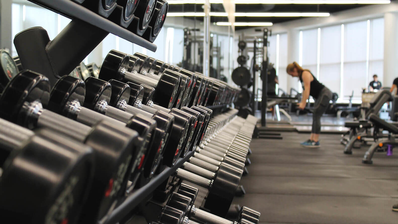 a woman lifts weight in a college gym