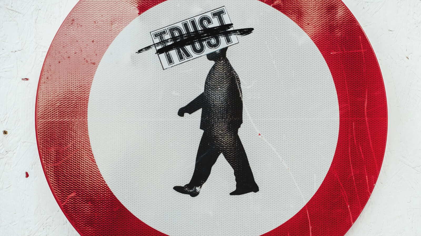 a red circle with a man in the center and the word trust scratched out
