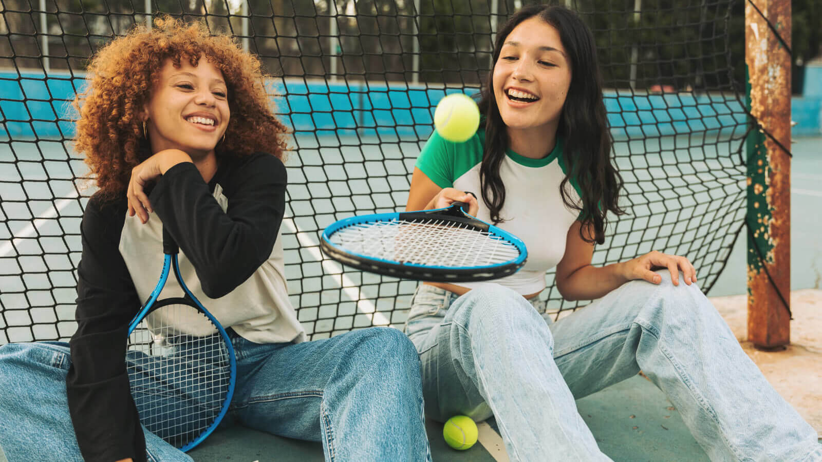 two girls laugh as they wait to play tennis