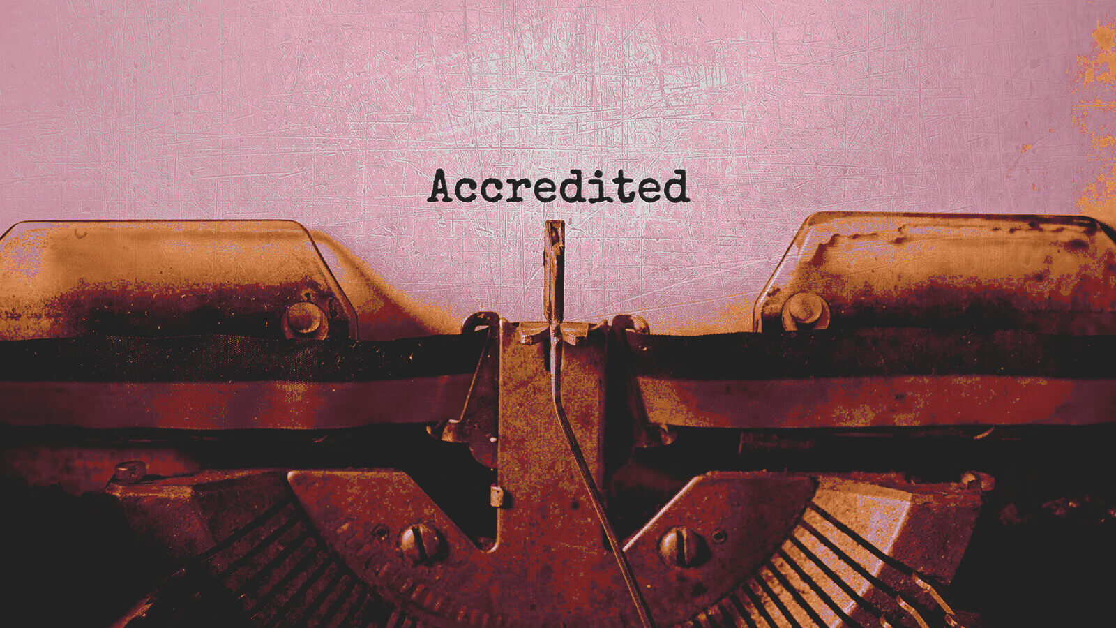 a typewriter and the word accredited typed out