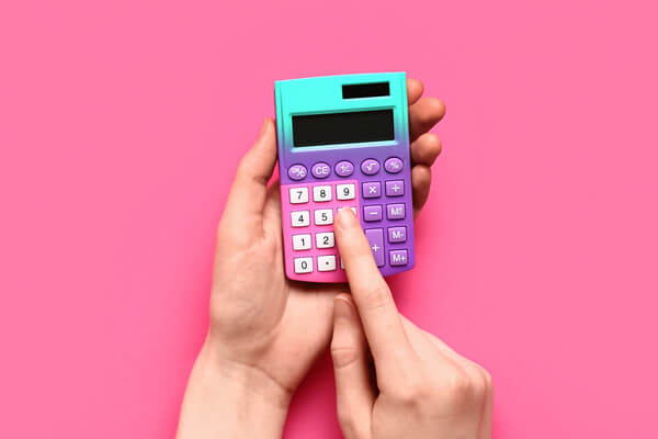 a colorful handheld calculator with a hand pressing a button