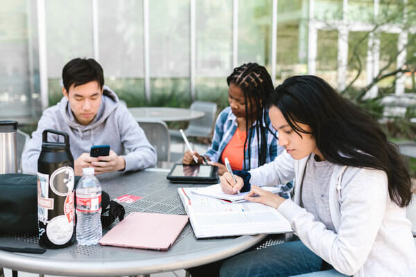 a group of students study at an table outside of their library