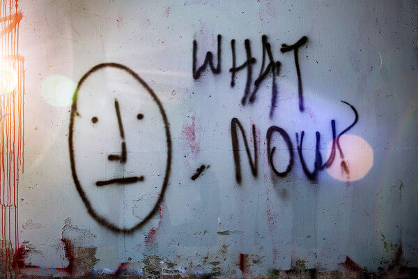 grafitti on a wall that says what now