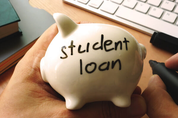 a small piggy bank with student loans written on it