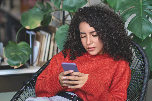 a girl student in a red sweater looks at her phone