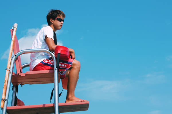 a lifeguard sits in a tall chair overlooking the beach and water